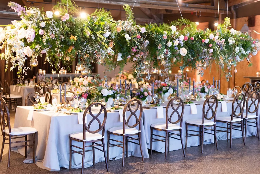 A suspended garden of flowers and greenery hanging the full length of a banquet table below