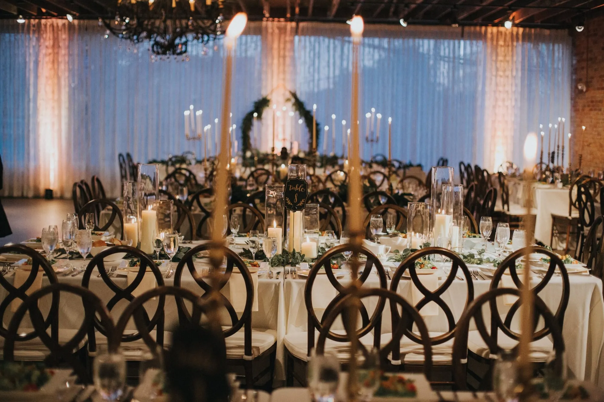 A dark, candlelit reception, tall tapers running the length of the tables
