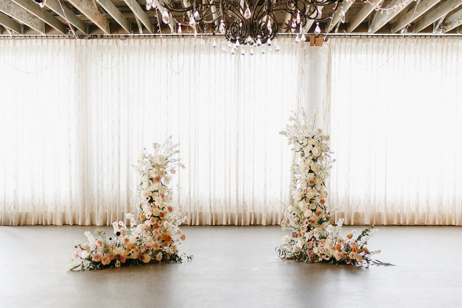 A white draped ceremony backdrop flanked by two floral pillars
