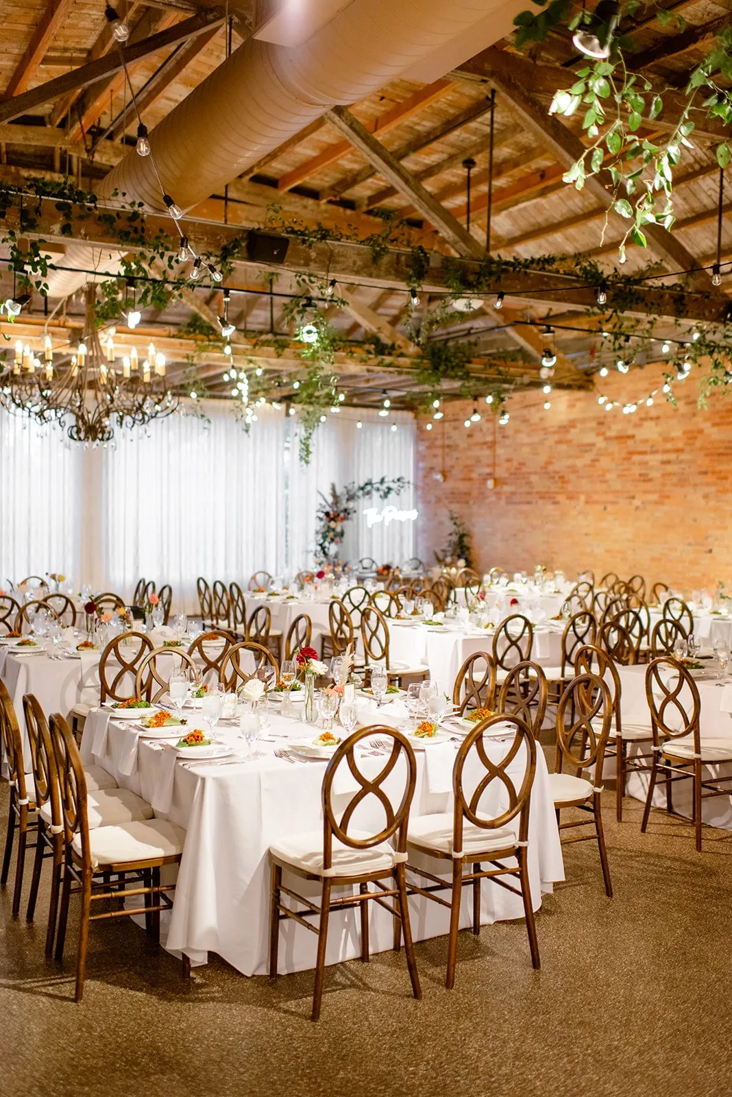 Round tables in daylight beneath a ceiling of suspended greenery