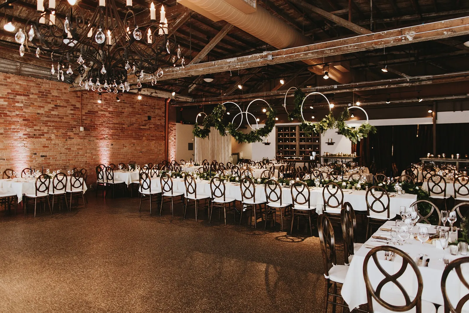 Long tables in white linens the length of the room, the brick uplit, set for a seated dinner