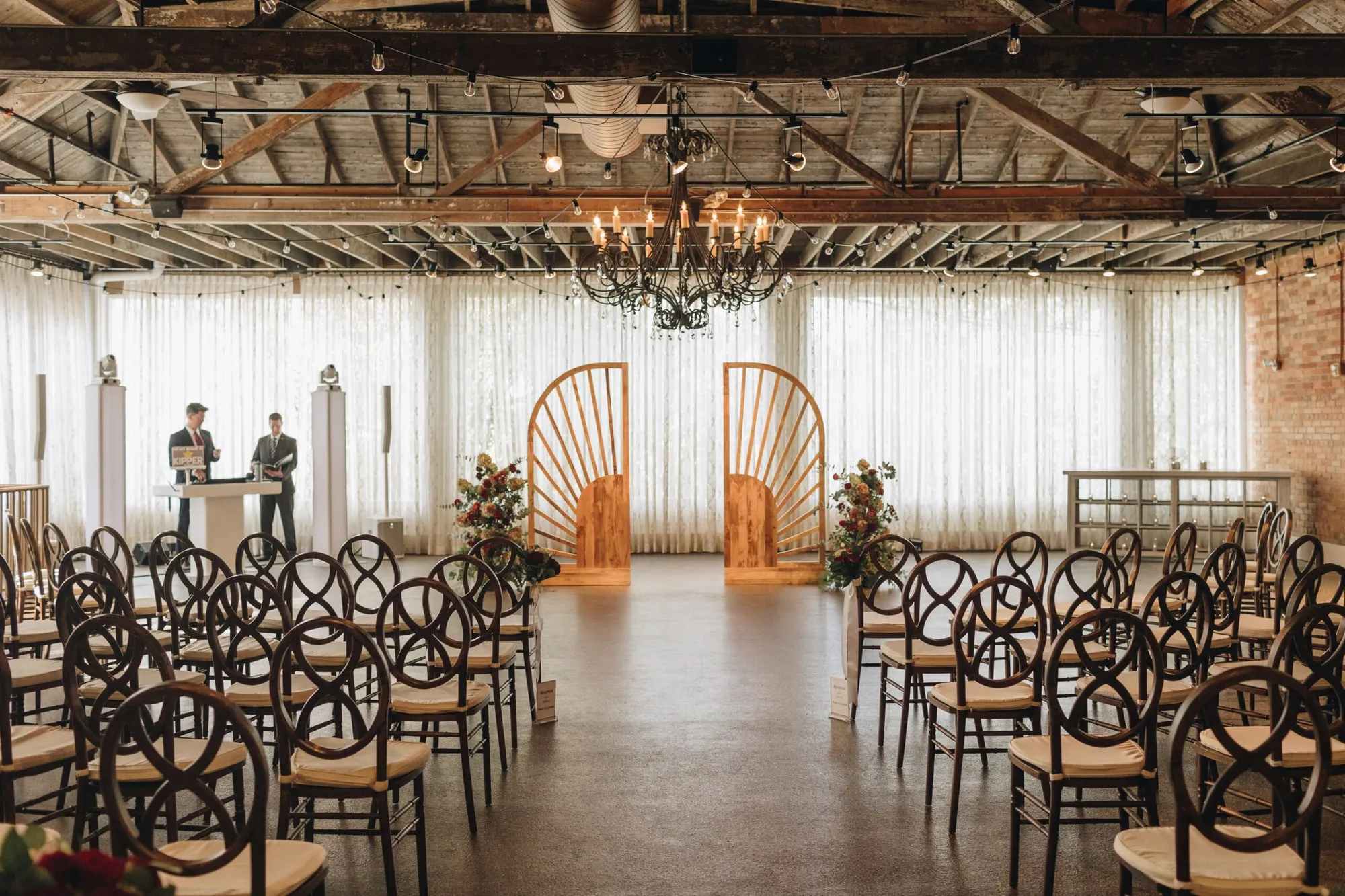 A ceremony set toward tall fan-backed wooden doors, chairs in rows either side