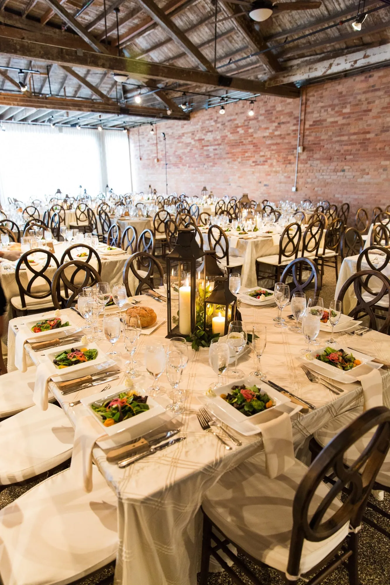 A place setting in close up, a glass lantern and folded linen on the table