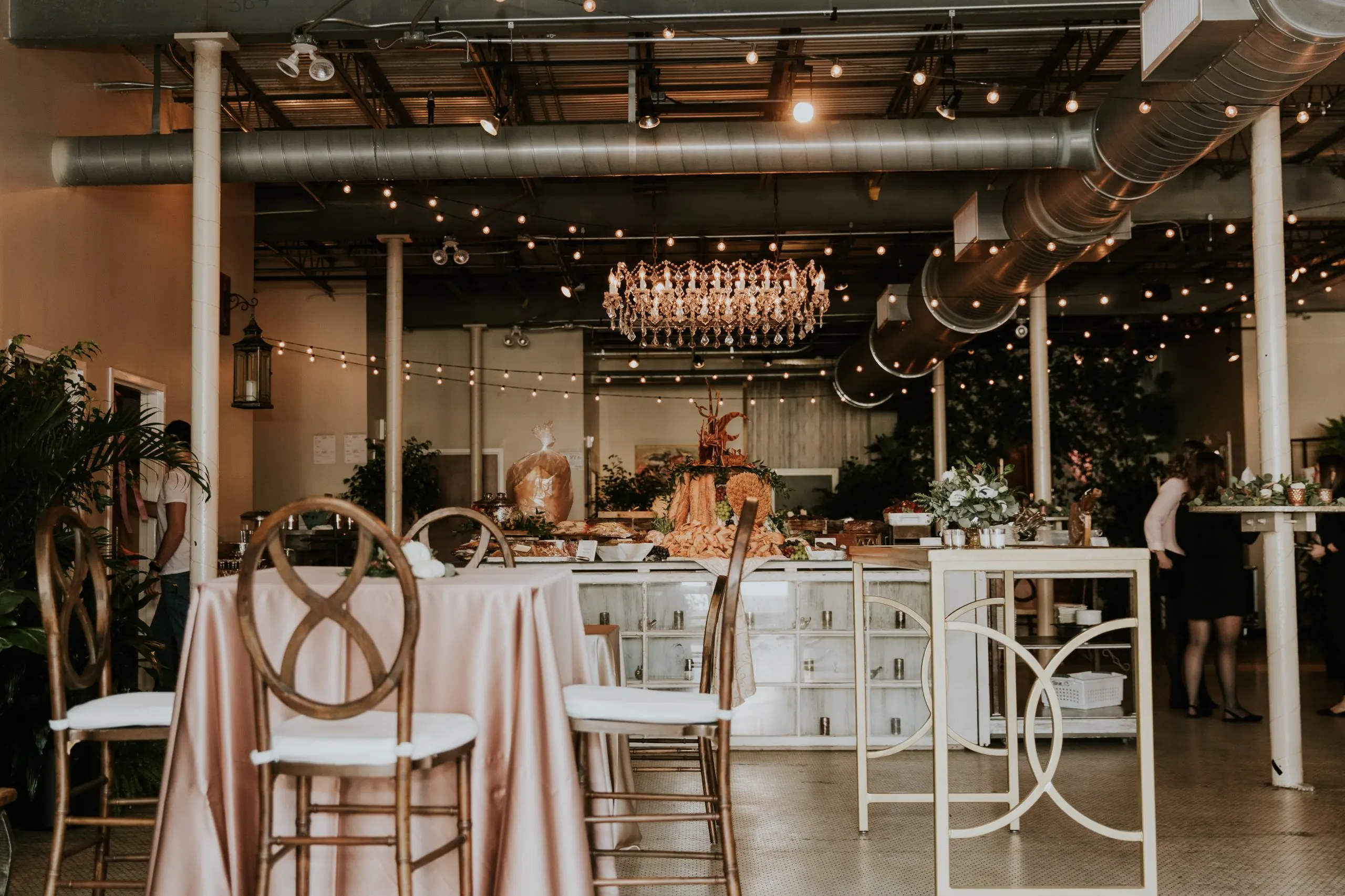 The bar and lounge area lit by a chandelier and string lights against the brick