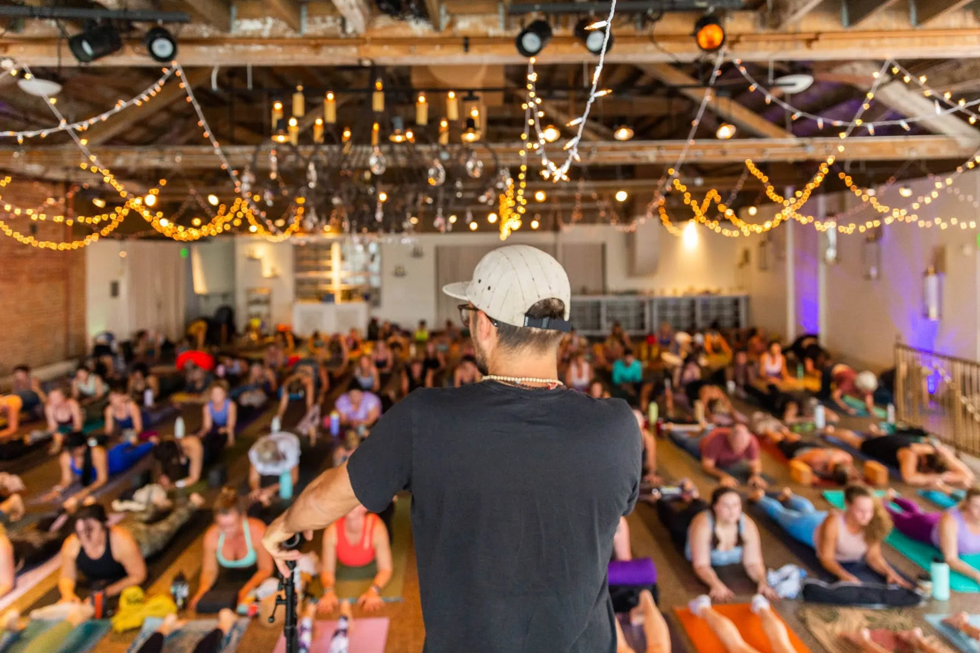 An instructor leading a large yoga class filling the floor of the room